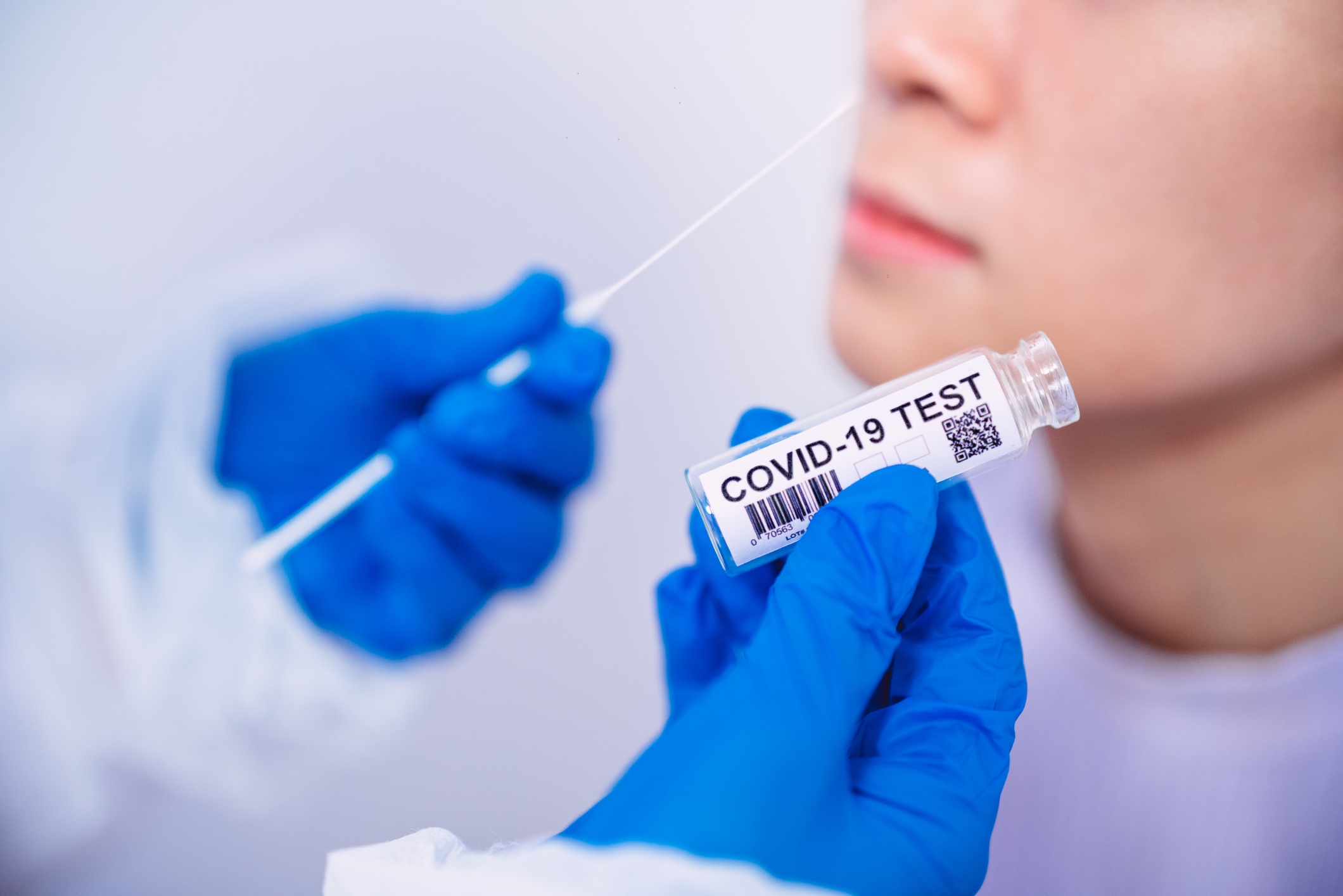 Uma pessoa colocando um cotonete no nariz de outra para fazer o teste de RT-PCR.