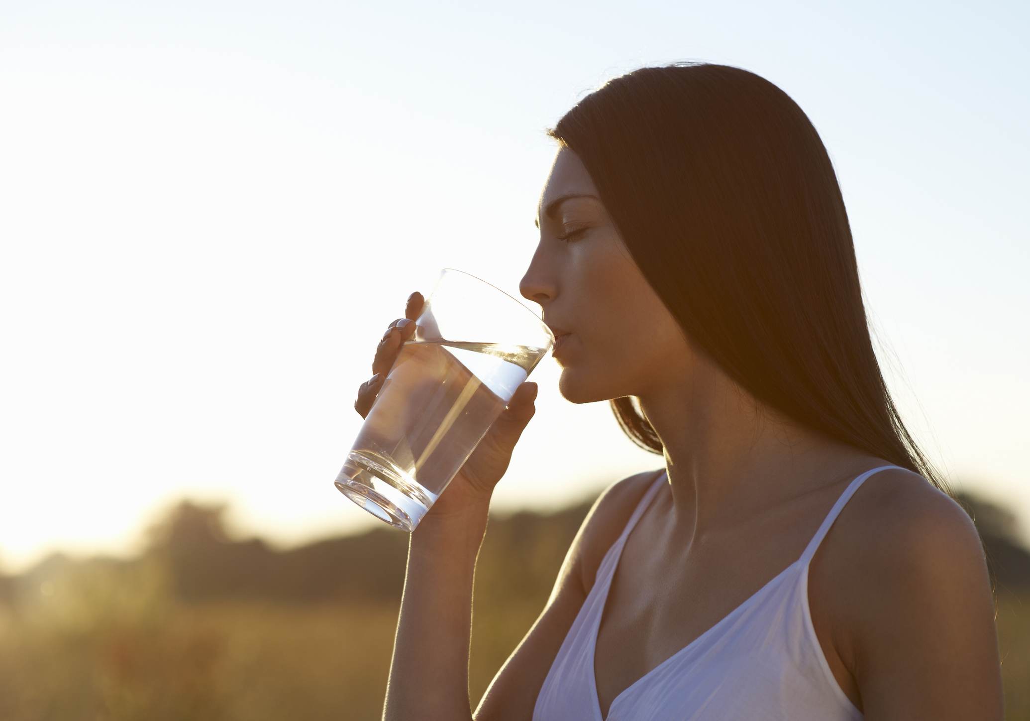 Mulher bebe água para lidar com sintomas de desidratação